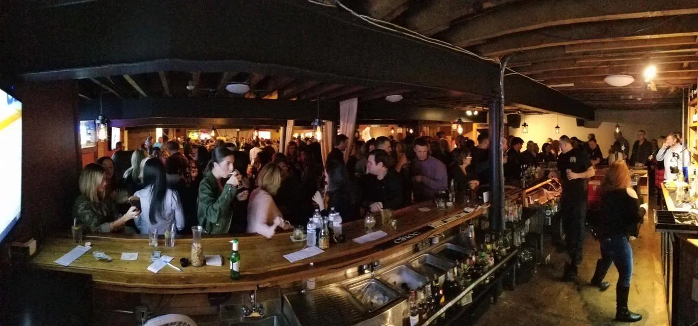 Friends gathered around the warmly lit wooden bar at Rock Bottom, downstairs at Rocco's