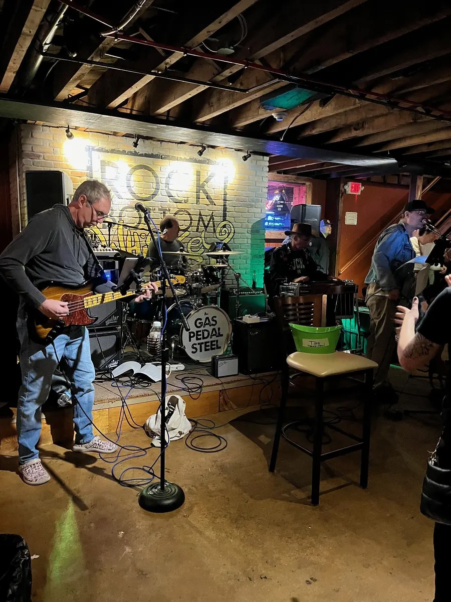 Musicians playing guitar and drums in the downstairs whiskey bar